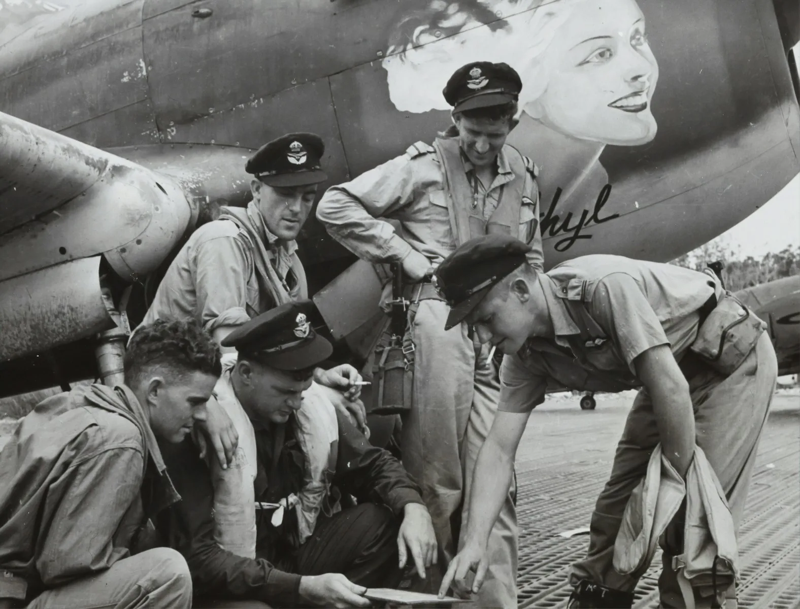 grayscale photo of men in uniform sitting on concrete wall